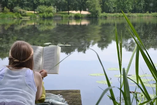 A woman reading beside a lake
