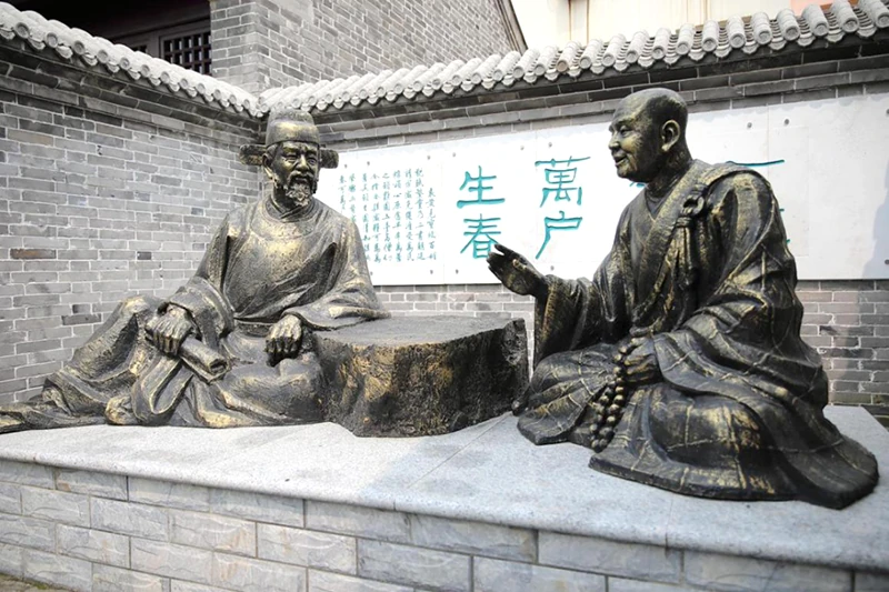 Two bronze figures facing each other in conversation in a courtyard