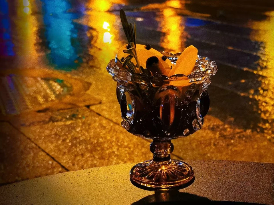 A cocktail with an orange slice under nighttime lighting