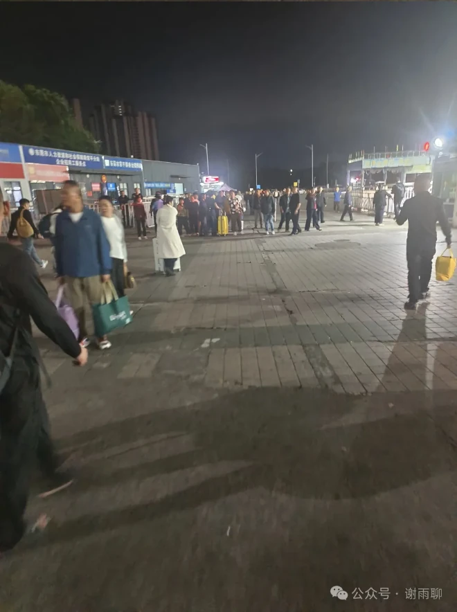 Travelers in the station square at night